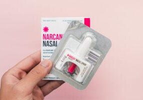 Hand holding a Narcan Evzio Naloxone nasal spray opioid drug ove